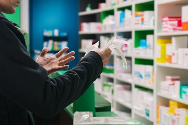 Shocked upset man holding bills for the purchase of medicine at a pharmacy