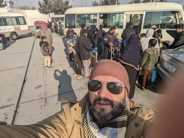 Stern is pictured taking a selfie with all the evacuees in the background boarding buses to flee Afghanistan.